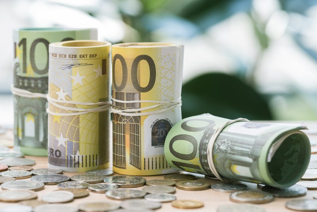 selective focus of euro banknotes in rolls with rubber bands and coins on table