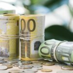 selective focus of euro banknotes in rolls with rubber bands and coins on table