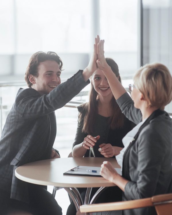 Happy successful business team giving a high fives gesture as they laugh and cheer their success